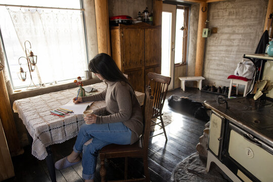 Woman coloring in book in cabin kitchen
