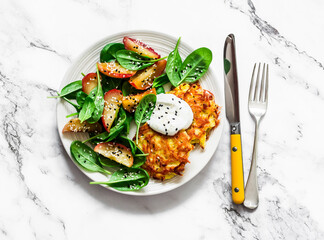 Potato latkes with baked apples, spinach salad on a light background, top view