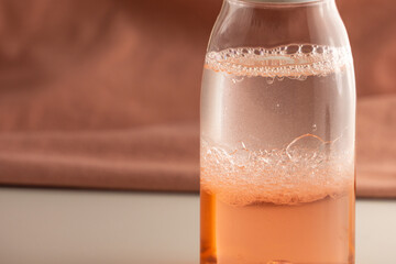 Two-phase makeup remover on a pink background. Foaming cleanser. Mixed two-phase cosmetic product.