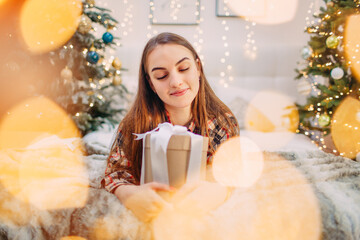 girl holding a christmas gift and enjoying cozy atmosphere