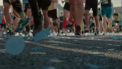 Soft focus shot of unrecognisable runners on city organised marathon, urban running race for charity. Confetti on finish or start line for participants