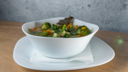 Fresh vegetable soup made of green bean, pea, carrot, potato, red bell pepper, tomato and leek in bowl.