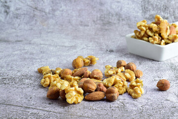 
Assorted dried fruits, walnuts, hazelnuts and almonds on a stone base and in a white rectangular plate.