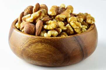 Assortment of nuts, walnuts, hazelnuts and almonds in a wooden bowl, light background.