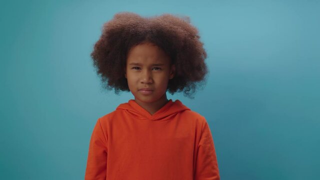 African American girl shows disagreement by shaking her head saying 'No' standing on blue background.