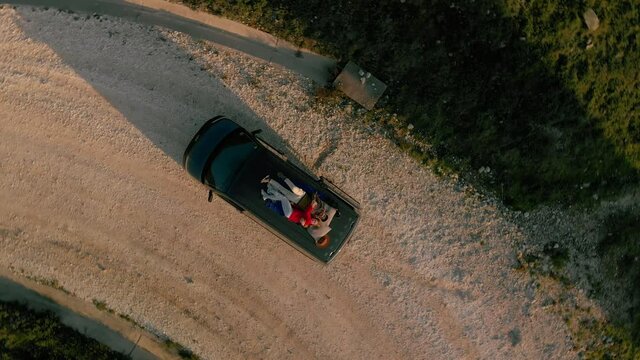 Top view with zoom out on romantic couple on date, laying on roof of car or van, watch stars or sky in natural national park, secluded camping site in wilderness, concept relationship goals