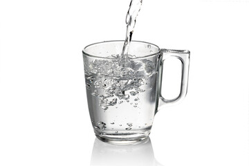 Fresh water pouring into glass with handle, isolated on white