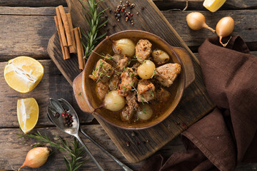 stifado - delicious mediterranean beef stew with onion bulbs, cinnamon and spices in a casserole, on a black wooden table, view from above, close-up
