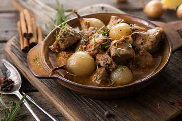 stifado - delicious mediterranean beef stew with onion bulbs, cinnamon and spices in a casserole,...