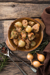 Stew. stifado - delicious mediterranean beef stew with onion bulbs, cinnamon and spices in a casserole, on a black wooden table, view from above, close-up