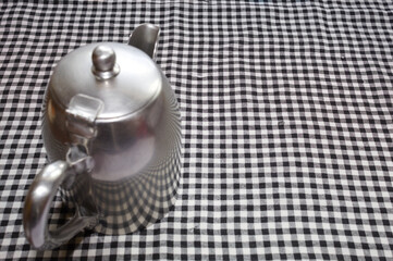 Metal kettle on a chess tablecloth