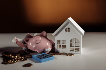 Broken piggy bank with coins and house model on a table
