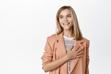 Cute little girl, child in blazer, holding hands on heart and smiling, express love and care,...
