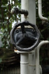 Old rusty black valve with white pipes