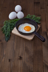 Fried egg in a small frying pan with a stand and whole white eggs