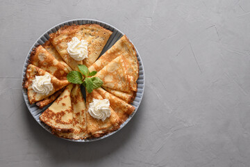 Russian thin pancakes or blini with whipped cream on grey table. Top view. Shrovetide. Space for...