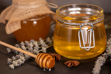 Flower honey in jars, and a wooden spoon for honey on a dark background