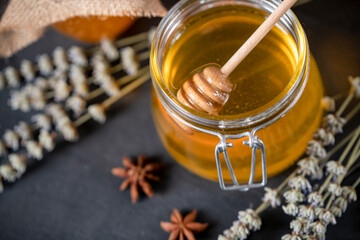 Flower honey in jars, and a wooden spoon for honey on a dark background