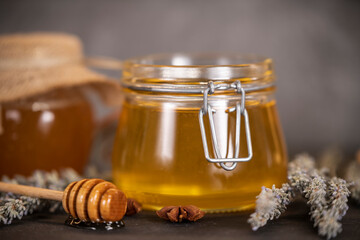 Flower honey in jars, and a wooden spoon for honey on a dark background
