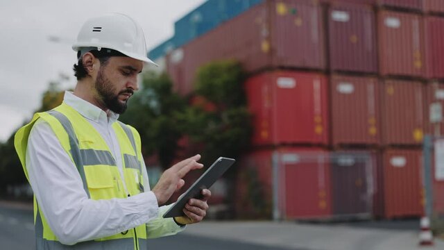 Man standing at cargor harbor with tablet in hands
