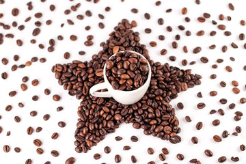 Cup of coffee and star made of roasted coffee beans on a white background. Scattered coffee beans. 