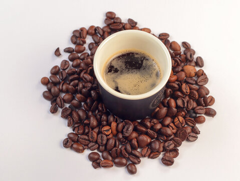 Cup of coffee and coffee beans. Coffee bean on white background with soft-focus and over light in the background.