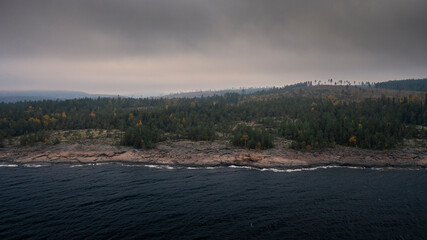 Rocky coast of Rotsidan with forest at Höga Kusten in east coast of Sweden from above on cloudy day.