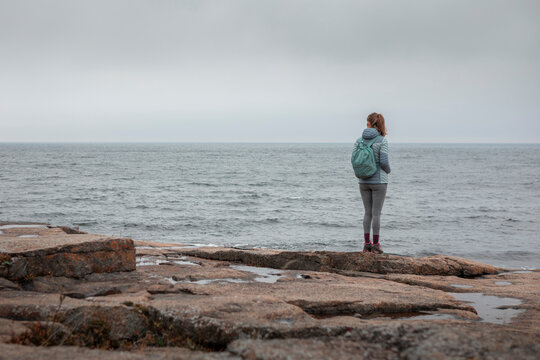 Woman on the rocky coast of Rotsidan at H&ouml;ga Kusten looking at se in the east of Sweden.