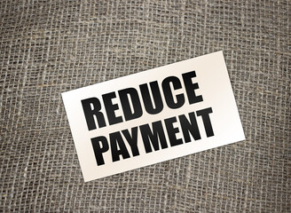 Reduce payment text on card on burlap canvas. business concept