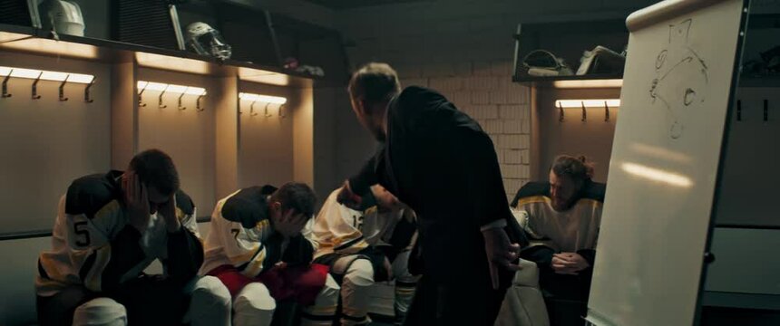 HANDHELD Angry disappointed coach yelling on players of ice hockey team in the locker room. Shoot with 2x anamorphic lens