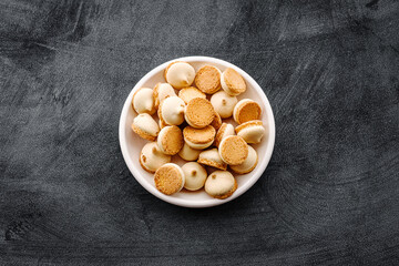 A plate of small sponge cookies on a black table