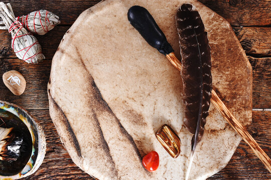 A top view image of a handmade leather meditation drum with sacred feather and sage smudge sticks.  