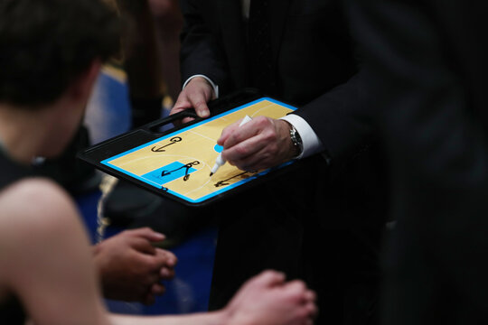 A Basketball Coach Draws Up A Play During A Timeout