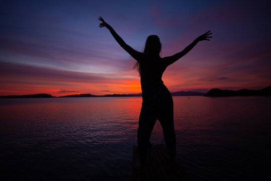 Silhuete Of A Young Female Posing On The Beach At The Purple Sunset