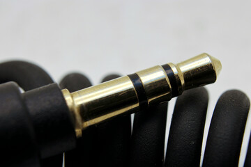 Closeup selective focus shot of 3.5mm audio jack connector resting on curled cable.