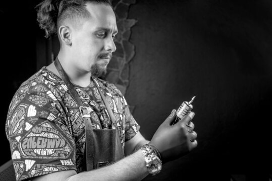 Tattoo artist with a tattoo gun in his salon