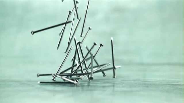 The nails slowly fall on the table. On a gray background. Filmed is slow motion 1000 fps.