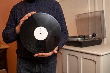 Man holding a vinyl record in front of the turntable