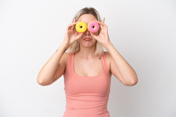 Young caucasian woman isolated on white background holding donuts in eyes with sad expression