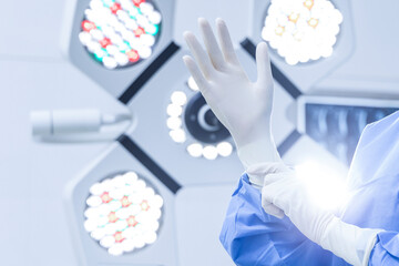 Fototapeta na wymiar A Close up photo of surgeon wearing protective surgical gloves inside modern operating room.
