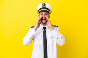 Airplane caucasian pilot isolated on yellow background shouting and announcing something © luismolinero