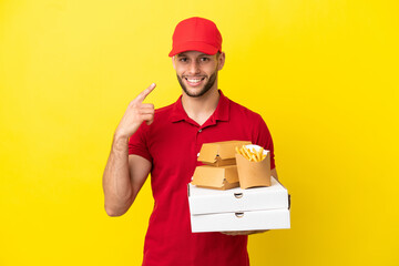 pizza delivery man picking up pizza boxes and burgers over isolated background giving a thumbs up...