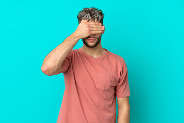 Young handsome caucasian man isolated on blue background covering eyes by hands. Do not want to see...