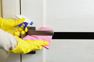 The woman washes and disinfects the doorknob. prevention of the spread viruses.