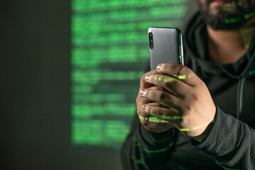 Man holding a smartphone in a room with green coding