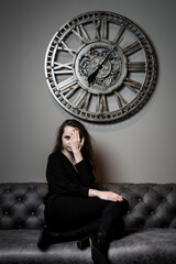 Girl and time. Beautiful young girl posing against the background of a wall clock - obrazy, fototapety, plakaty