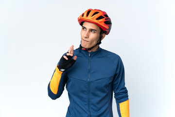 Young cyclist man isolated on background with fingers crossing and wishing the best