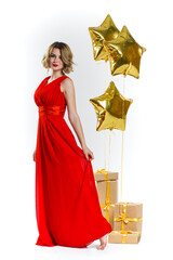 Party photo of elegance sexy lady in red dress with red lips and blond beautiful curly hair, smiling. Background of gold air balloons and gifts. Concept of the sale