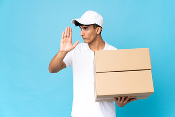 Delivery Argentinian man isolated on blue background making stop gesture and disappointed