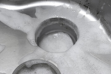 台所の流し台を泡の洗剤で掃除するイメージ